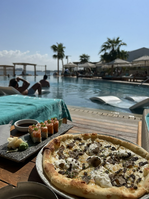 Enjoying pizza and sushi by the swimming pool during a vacation.