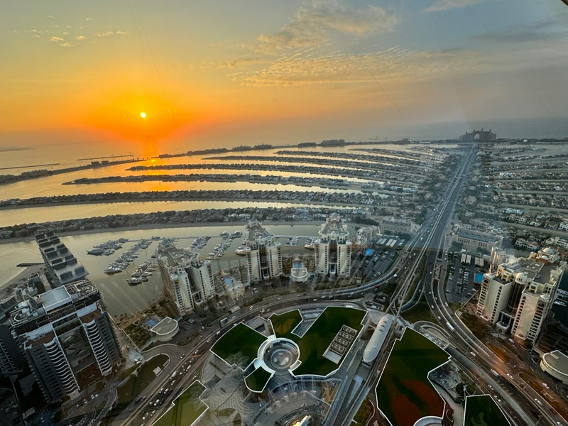 Aerial view of Dubai at sunset with vibrant colors and iconic buildings.