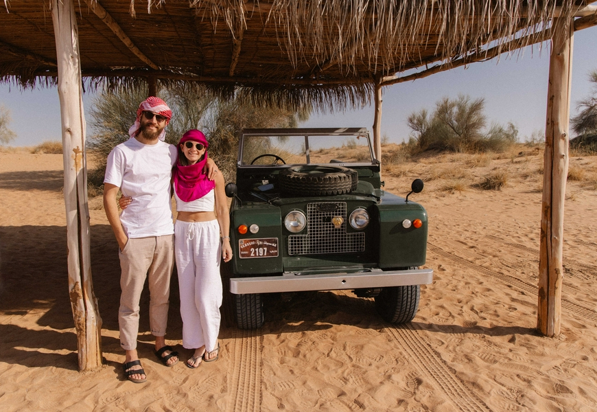 A jeep traversing a vast desert landscape with sandy terrain.