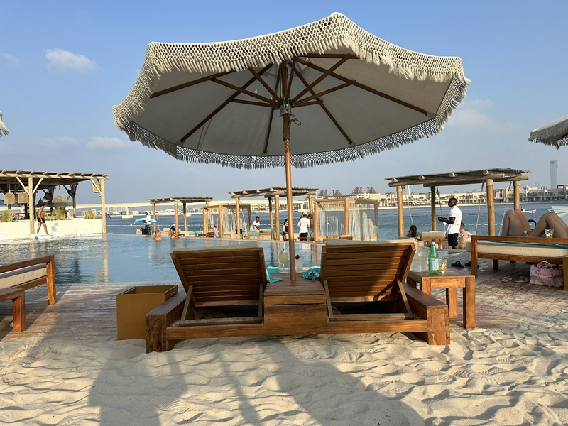 Scenic view of White Beach Dubai with sunbeds, umbrellas, and pool area.