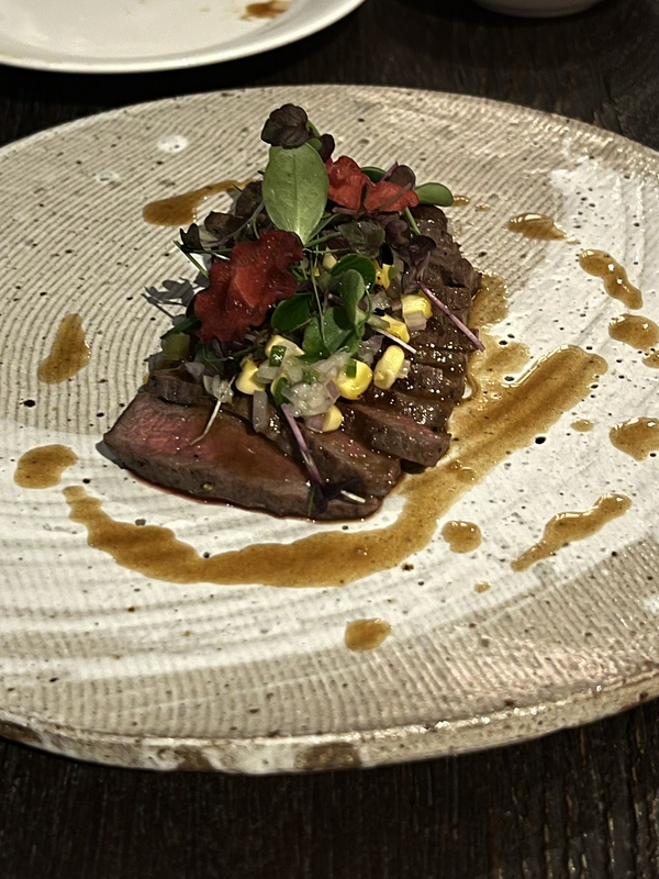 A gourmet plate featuring a succulent steak, vibrant garnishes, and rich sauce at Nobu.