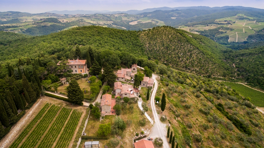 Aerial view showcasing the lush vineyards and rolling hills of the Tuscan countryside.