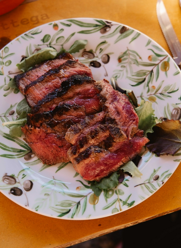 Grilled steak served with fresh leafy greens on a plate.