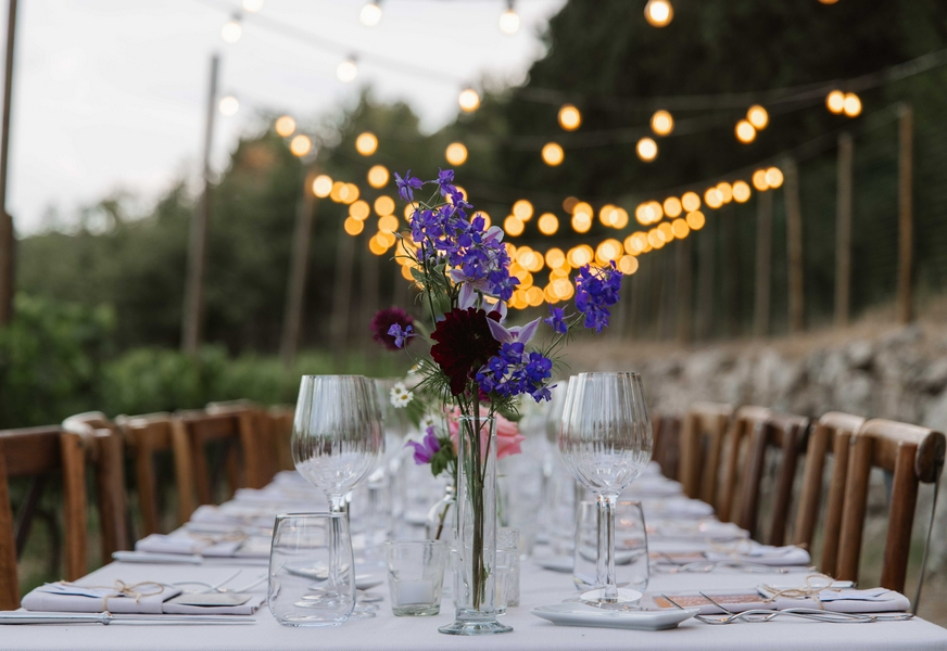 Outdoor dining setup in Tuscany surrounded by flowers and evening light.