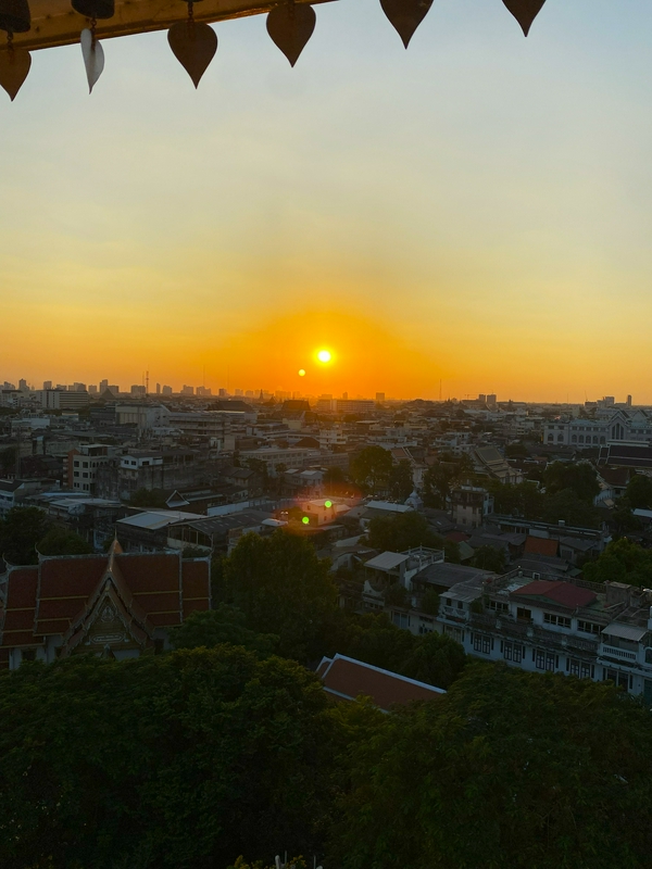 Visitors capturing sunset views from a mountain temple after a strenuous climb.