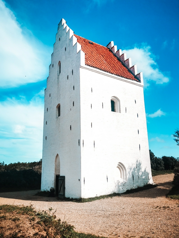 Buried church tower of Den Tilsandede Kirke in Denmark surrounded by sand dunes.