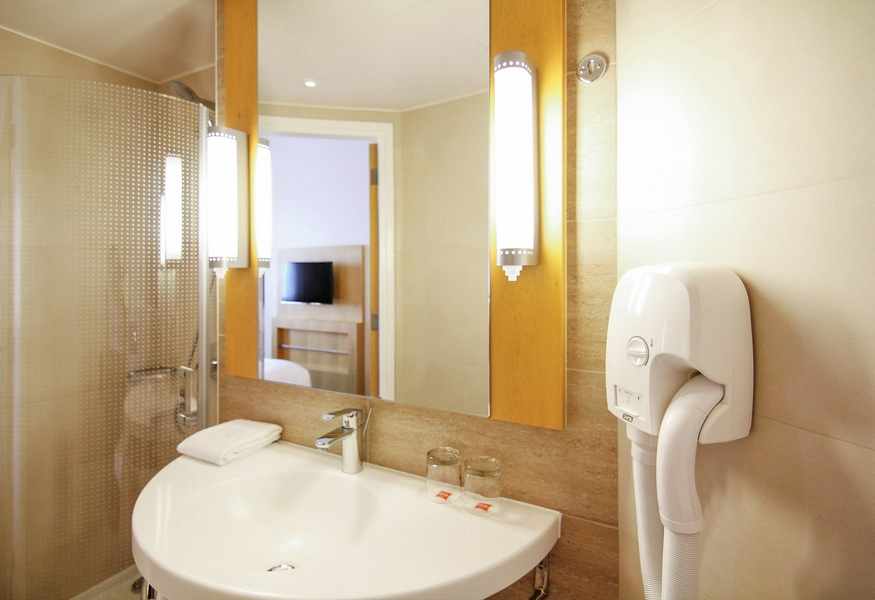 Spacious bathroom with modern amenities including sink, mirror, hairdryer, and fresh towels.