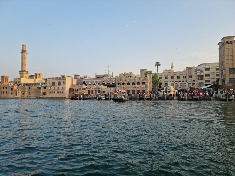 Scenic view of Dubai Old City featuring water, buildings, and a tower.