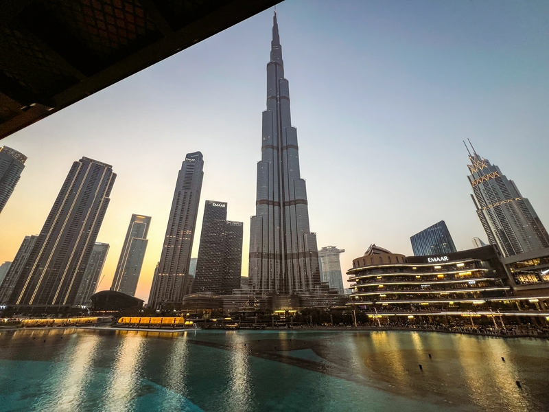 A stunning sunset view of Dubai's skyscrapers reflecting on tranquil waters.