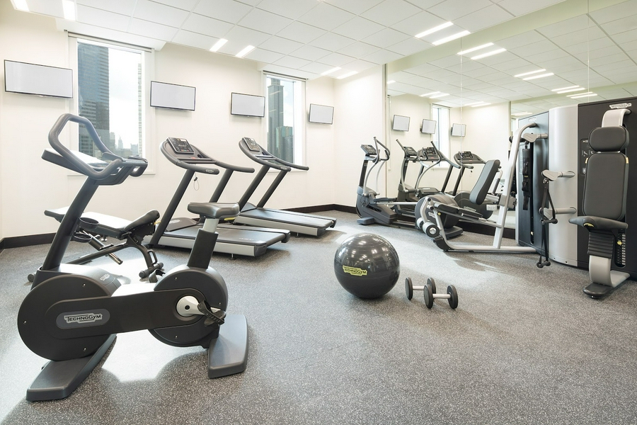 Modern gym with exercise equipment including treadmills and dumbbells.