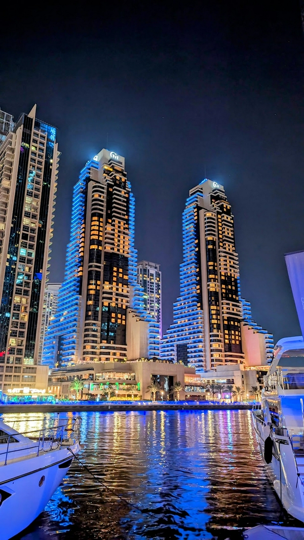 Dubai Marina cityscape at night, showcasing illuminated buildings and calm waters.
