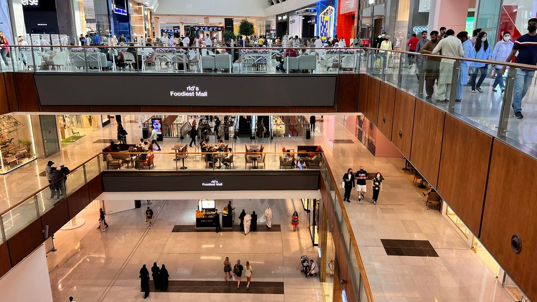 A bustling shopping mall with people enjoying shopping and dining.