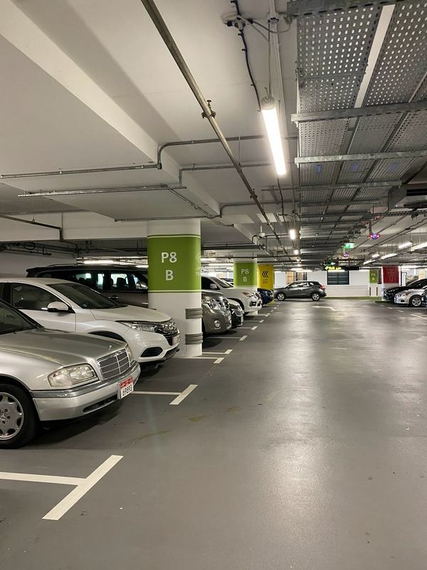 Indoor parking garage at Dubai Mall featuring various cars and concrete structure.