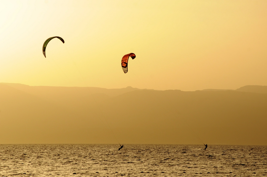 Kitesurfing at sunset in Aqaba with ocean silhouettes.
