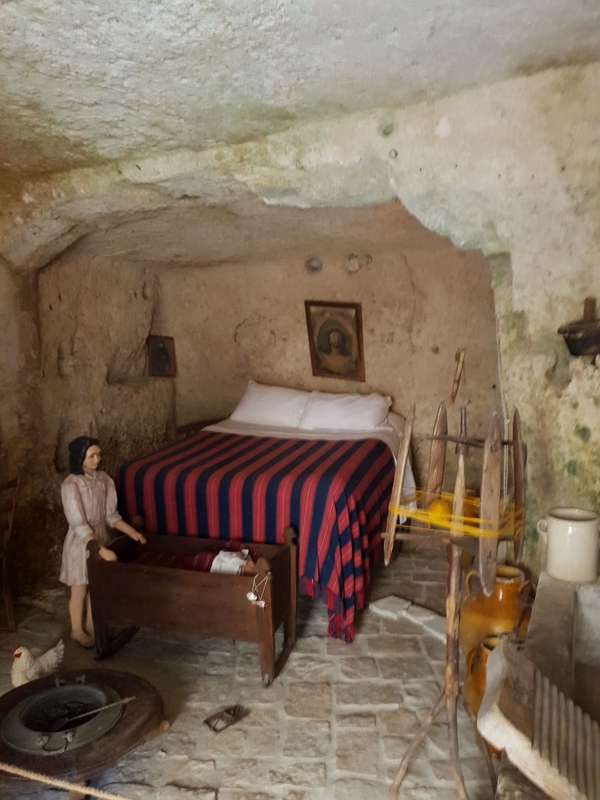A rustic interior showcasing a bed with a blanket and a rock wall.