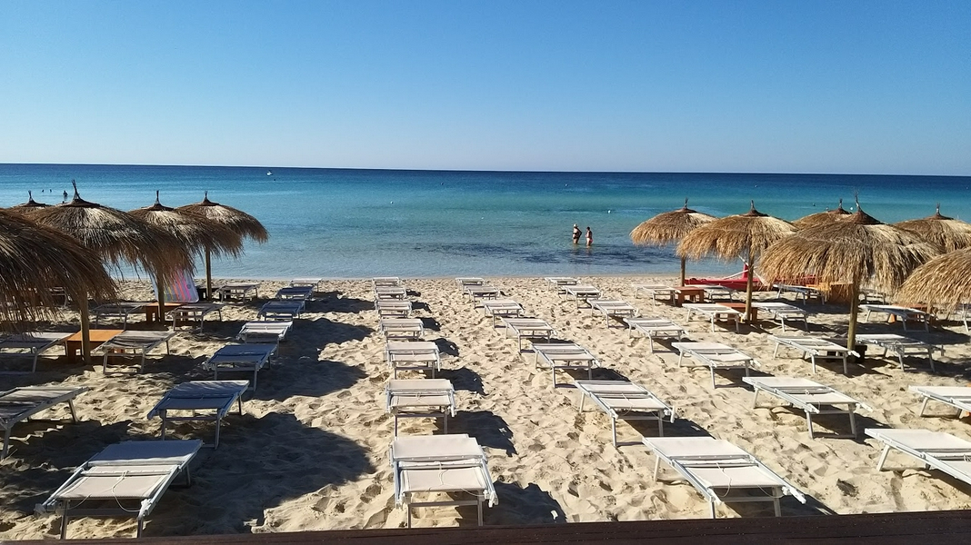 Punta Prosciutto Beach with golden sand and vibrant blue ocean waters.
