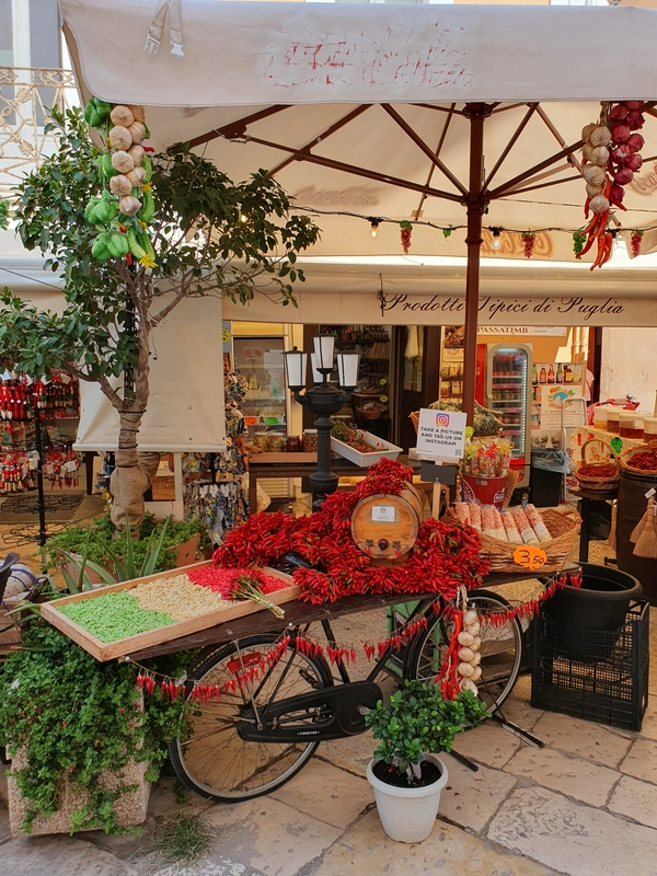 A vibrant market scene in Bari showcasing fresh produce, bicycles, and traditional storefronts.
