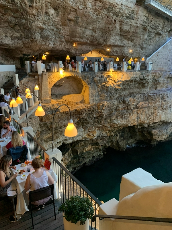Outdoor dining at Grotta Palazzese with ocean views and cliffs.