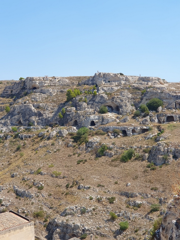 Rocky landscape of Matera with ancient cave dwellings and clear sky.