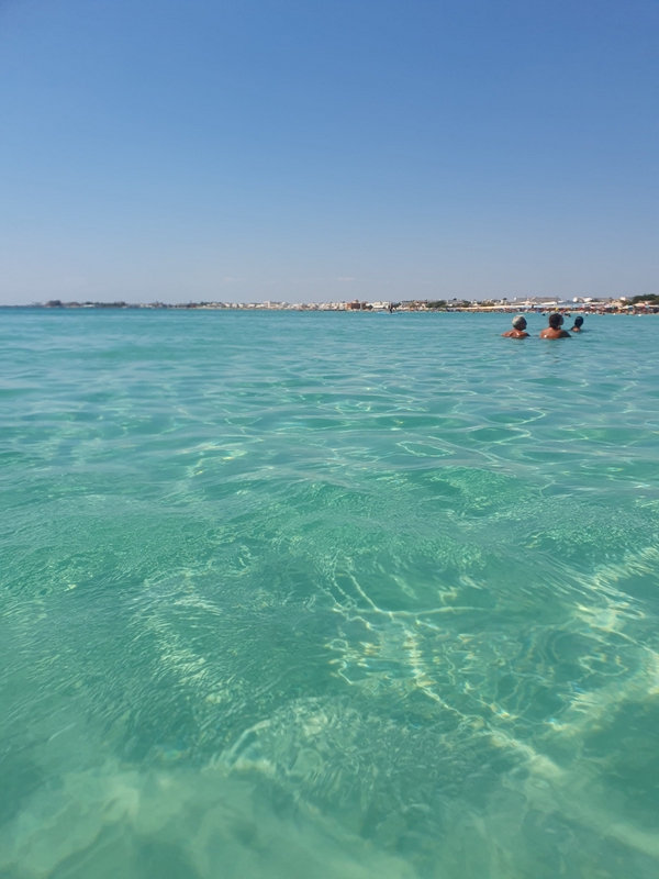 A serene beach with clear blue ocean and vibrant sky, showcasing nature's beauty.