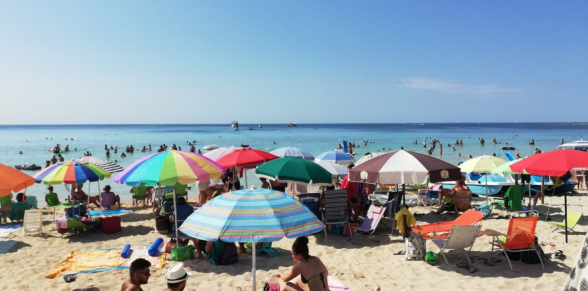Torre Lapillo Beach with clear waters and colorful umbrellas