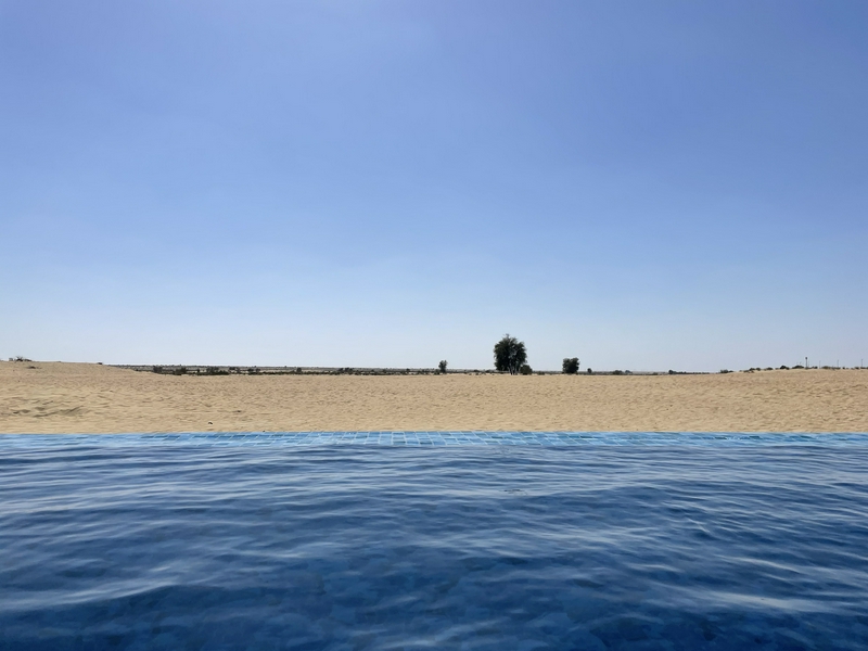 Breathtaking view of a desert landscape with sunset over a luxury infinity pool.