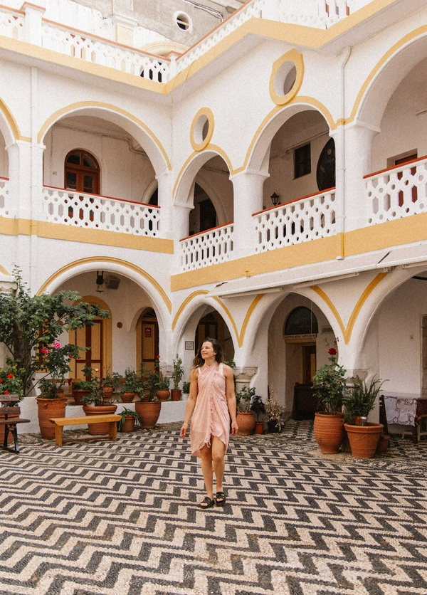Courtyard of the Holy Monastery of Taxiarch Michael with arches and potted plants.
