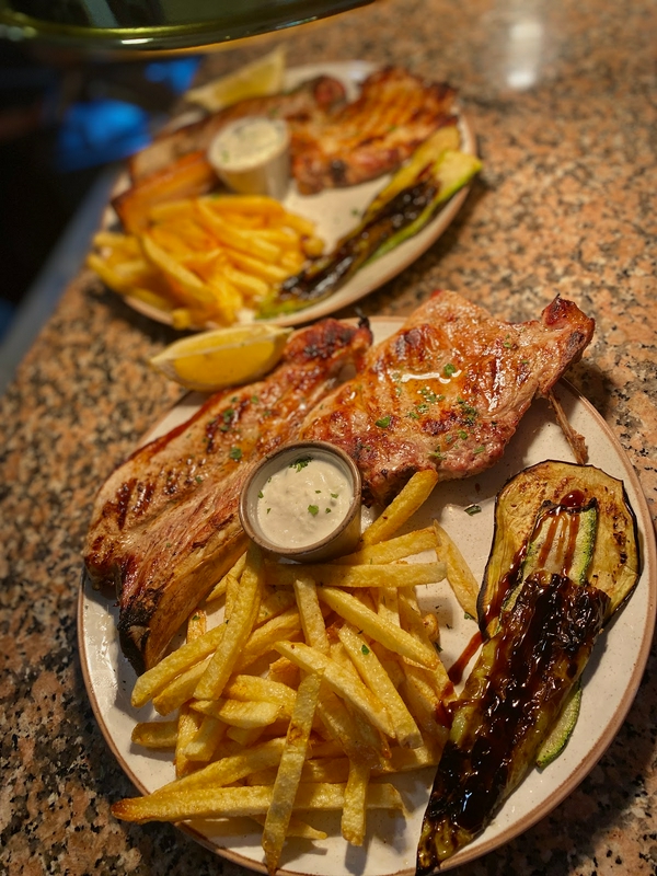 A delightful presentation of grilled meat, fries, and fresh vegetables.