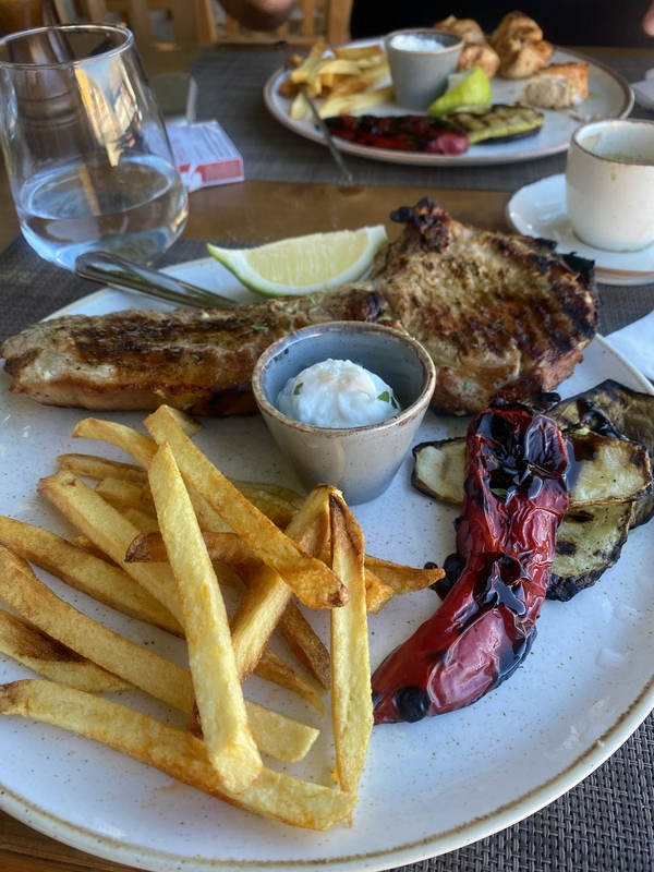 A plate of grilled meat with french fries and grilled vegetables.