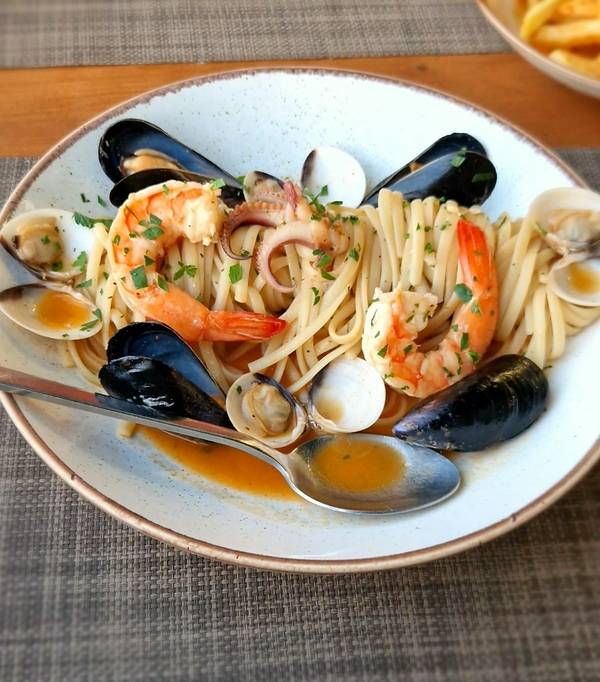 A plate of seafood pasta garnished with shrimp, mussels, and clams.